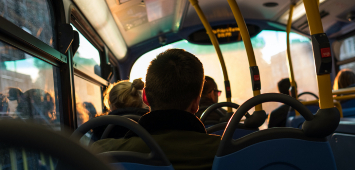 A silhouette of a man sitting on the bus, facing the front.